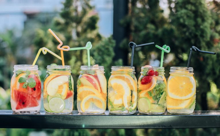 Photo of jars of watermelon and orange in glass jars ogf water with straws.