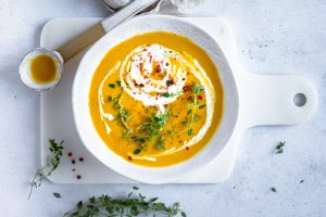 Photo of a bowl of pumpkin and ginger soup with a spoon.