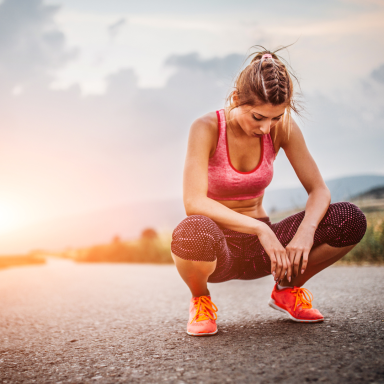 Photo of a female athlete kneeling down on the ground as she is exhausted.