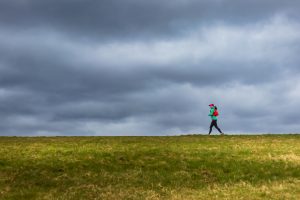 woman running through a field with a stormy sky in the background