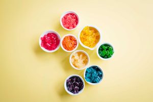 8 colourful bowls of gelatin gummies on a table