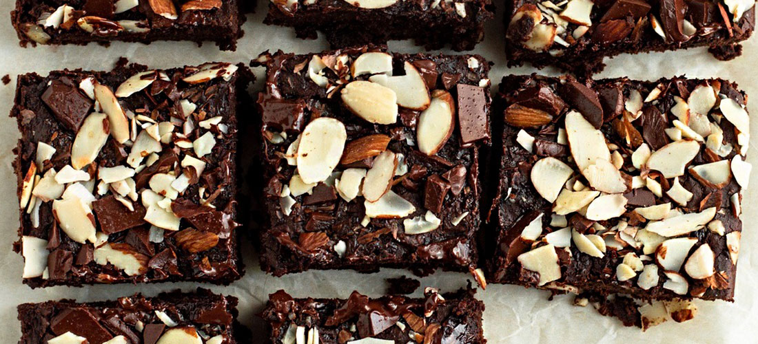 top down view of brownies on parchment paper with slivered almonds over top