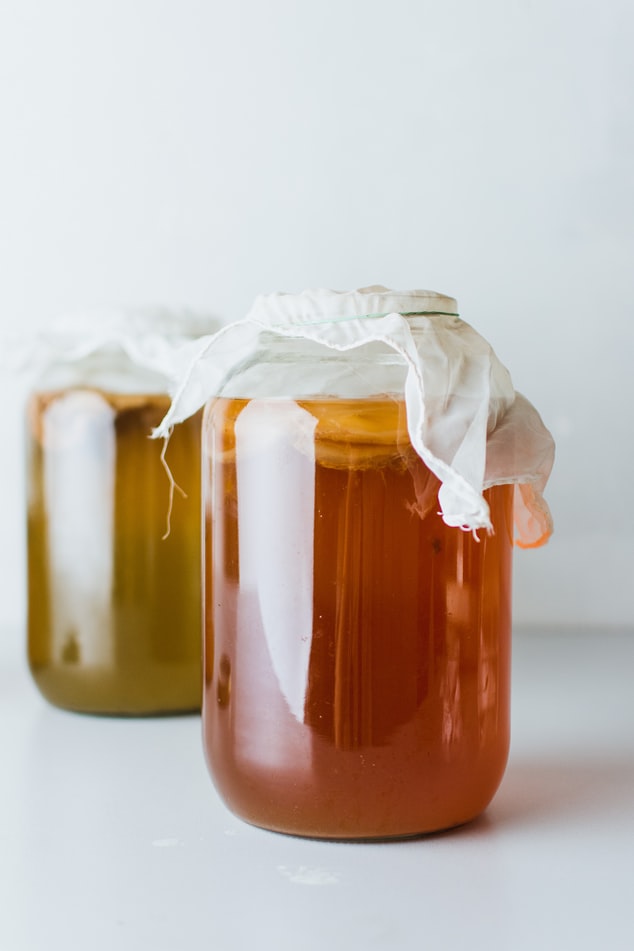 jar of kombucha with muslin cloth over top and second jar in background